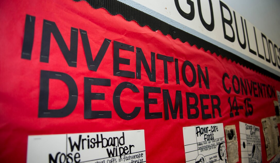 An Invention Convention sign is displayed on the wall of the gymnasium at Spangdahlem Middle High School at Spangdahlem Air Base, Germany, Dec. 15, 2015. The convention is a two-day event where students from the fifth to the eighth grades display their inventions to the base community. (U.S. Air Force photo by Airman 1st Class Luke Kitterman/Released)