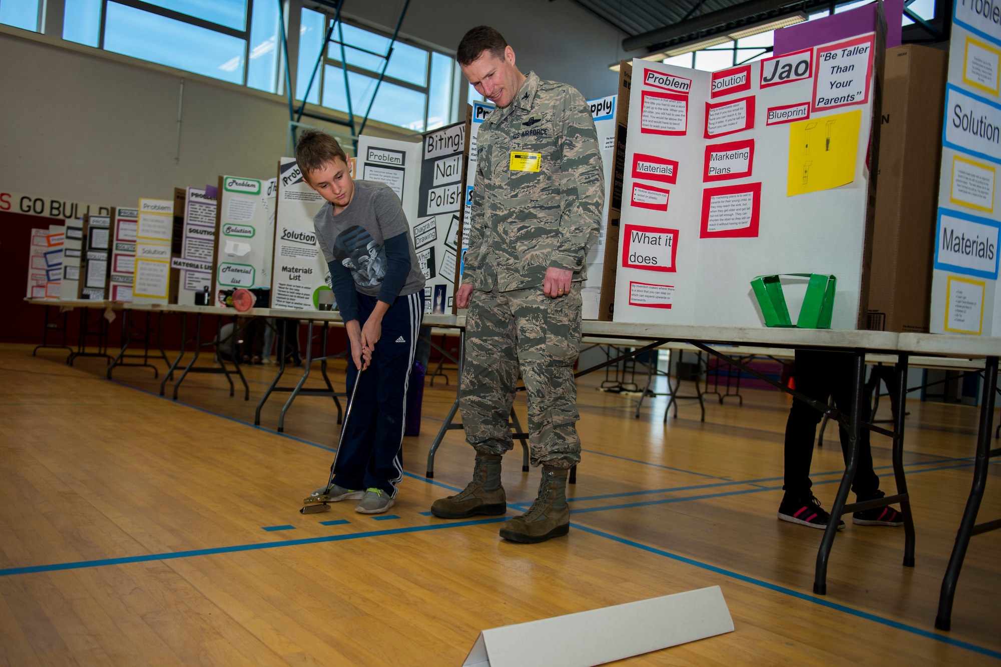 A student shows his invention of a “laser putter” to U.S. Air Force Col. Steve Horton, 52nd Fighter Wing vice commander, during the Invention Convention at Spangdahlem Middle High School at Spangdahlem Air Base, Germany, Dec. 15, 2015. The students explained and demonstrated their inventions to Horton and a board of judges. (U.S. Air Force photo by Airman 1st Class Luke Kitterman/Released)