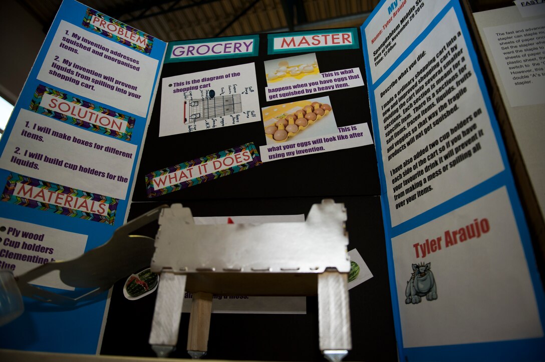A display board labeled “Grocery Master” stands behind an example model during the Invention Convention at Spangdahlem Middle High School at Spangdahlem Air Base, Germany, Dec. 15, 2015. Students from the fifth to the eighth grades created and explained their own inventions as part of the convention. (U.S. Air Force photo by Airman 1st Class Luke Kitterman/Released)