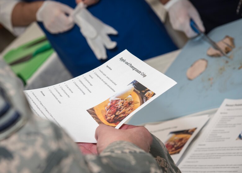 PETERSON AIR FORCE BASE, Colo. – A Peterson Airman picks up one of the three healthy recipes made available by the Peterson Health and Wellness Center for the Peterson Air Force Base Commissary Food Demo, Dec. 9, 2015. The HAWC provided the recipes and chefs from the Aragon Dining Facility prepared samples, which were offered to customers at the commissary to demonstrate how healthier options for the holidays still taste good. (U.S. Air Force photo by Senior Airman Rose Gudex)