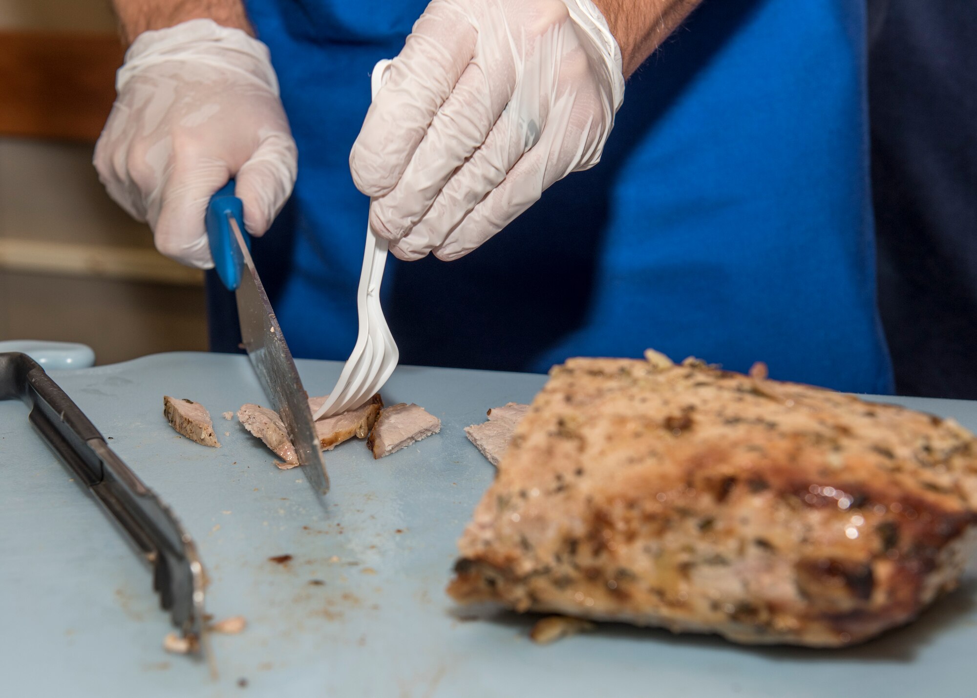 PETERSON AIR FORCE BASE, Colo. – A 21st Force Support Squadron dining facility journeyman cuts up a pork loin at the Peterson Air Force Base Commissary Food Demo, Dec. 9, 2015. Aragon Dining Facility prepared the samples following healthier holiday recipes provided by the Peterson Health and Wellness Center. (U.S. Air Force photo by Senior Airman Rose Gudex)