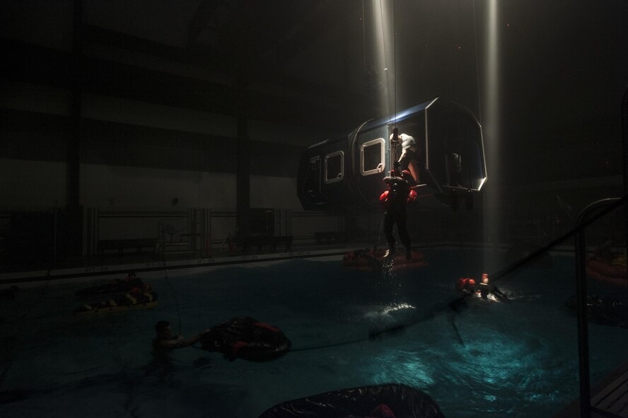 Survival, Evasion, Resistance and Escape instructors hoist Water Survival students into a training fuselage during a scenario Dec. 8, 2015, at Fairchild Air Force Base, Wash. The primary focus of the Water Survival Course is to prepare military members for having to escape an aircraft while over the ocean. (U.S. Air Force photo/Airman 1st Class Sean Campbell)