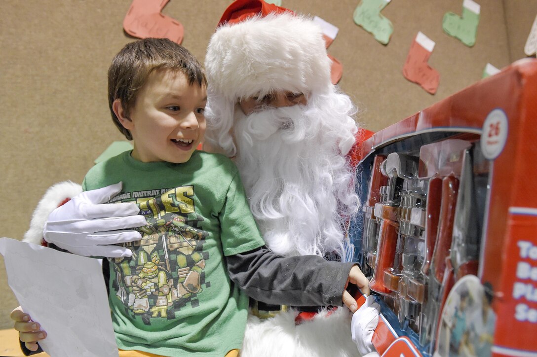 Xavier Hall, 4, receives a new toy from Santa Claus, played by U.S. Marine Corps Sgt. Mauricio Sandoval, during a Toys for Tots event in Nikolai, Alaska, Dec. 11, 2015. The U.S. Marine Corps Reserve runs the program to use toys to deliver a message of hope to less fortunate children. This year three teams of Marines traveled in sub-zero temperatures via snow machine to remote villages near Kotzebue, Galena and McGrath to deliver toys to children. U.S. Air Force photo by Alejandro Pena