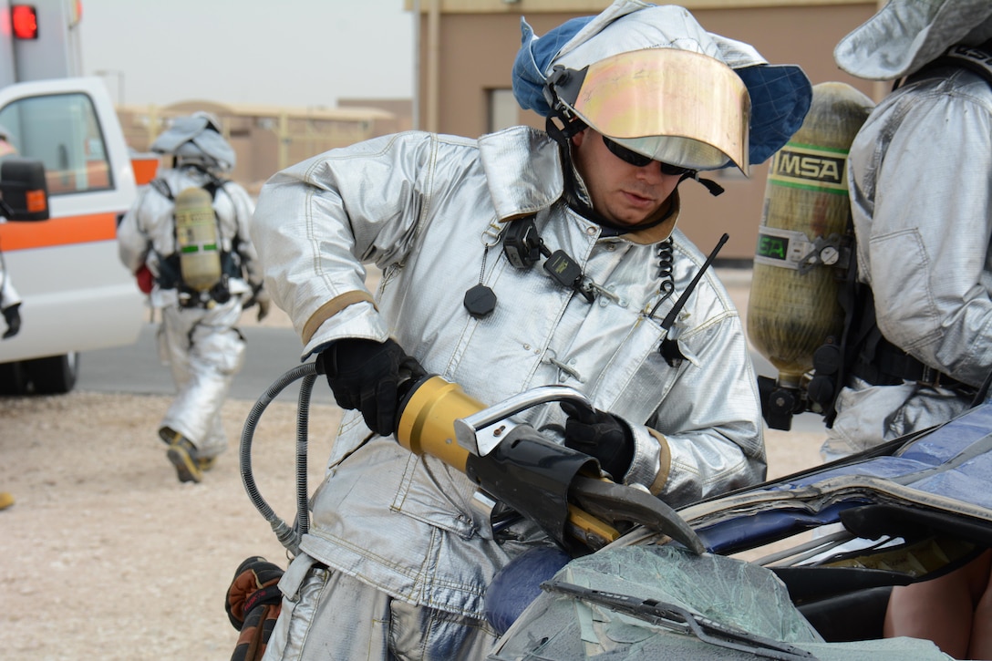 A 379th Expeditionary Civil Engineer Squadron firefighter uses the Jaws of Life to take the roof off a car during an exercise at Al Udeid Air Base, Qatar Dec. 15. The exercise consisted of a car accident with eight victims; two were trapped inside the car. More than 50 first responders participated in the exercise. (U.S. Air Force photo by Tech. Sgt. James Hodgman/Released)