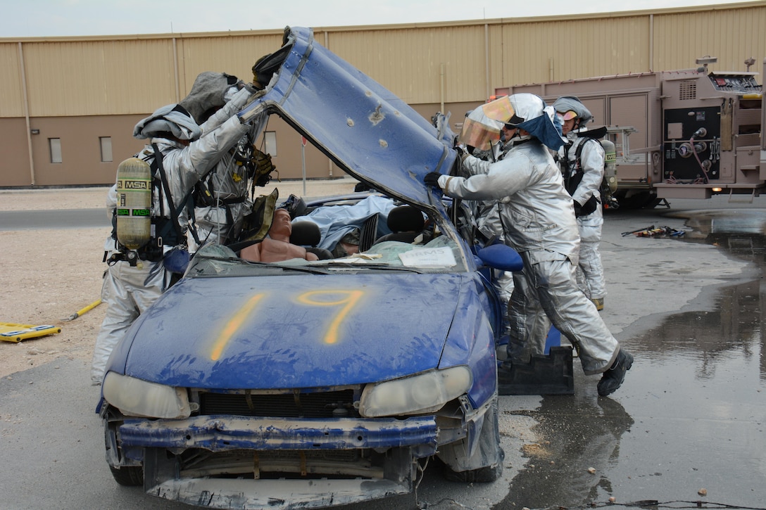 Firefighters assigned to the 379th Expeditionary Civil Engineer Squadron take the roof off of a car during an exercise at Al Udeid Air Base, Qatar Dec. 15. The exercise consisted of a car accident with eight victims; two were trapped inside the car. More than 50 first responders participated in the exercise. (U.S. Air Force photo by Tech. Sgt. James Hodgman/Released)