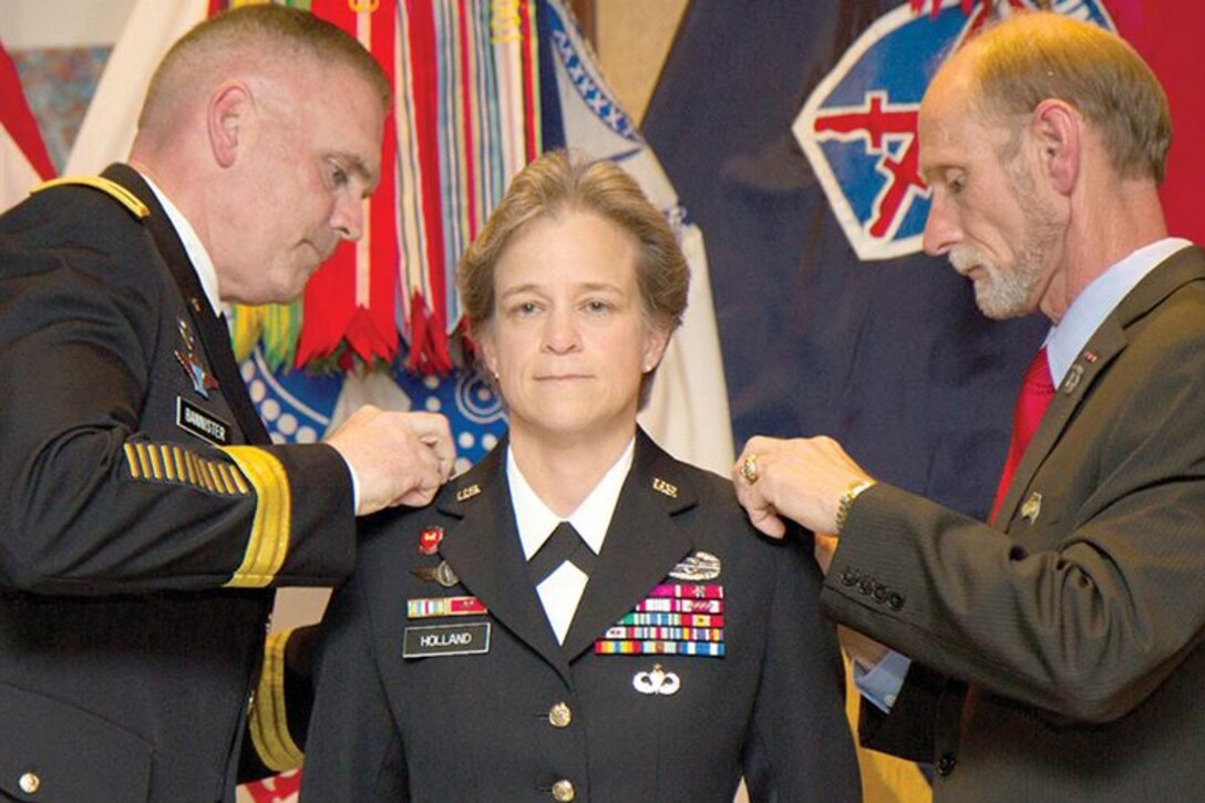 Brig. Gen. Diana Holland becomes the first woman to hold the title of deputy commanding general for support in a light infantry division during her promotion ceremony to brigadier on Fort Drum, N.Y., July 29, 2015. Her husband, James Holland Jr., right, and Army Maj. Gen. Jeffrey L. Bannister, 10th Mountain Division and Fort Drum commander, pin on her stars. U.S. Army photo by Spc. Osama Ayyad