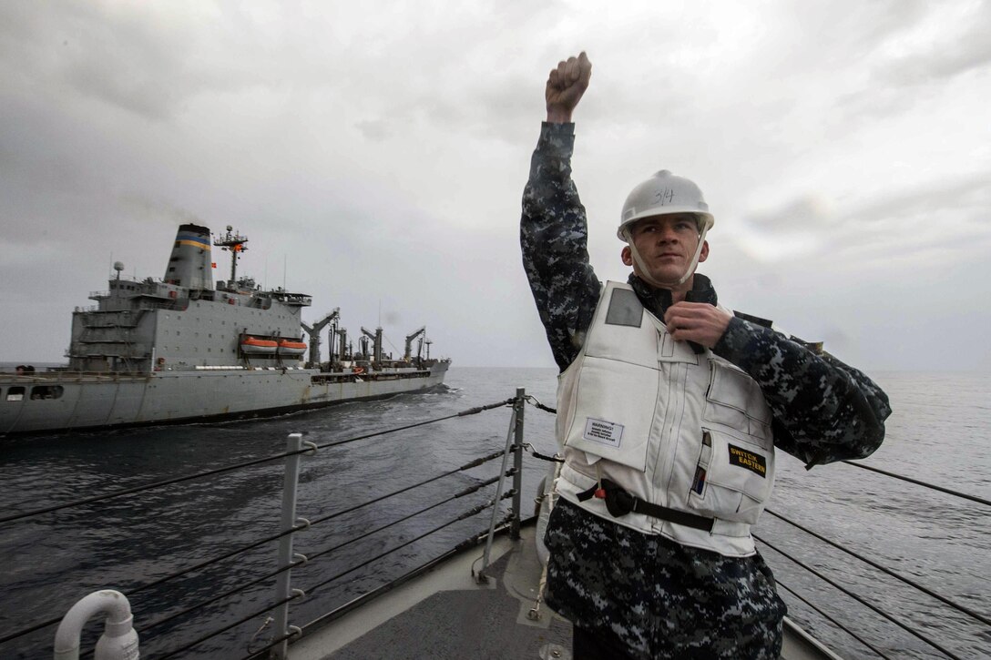U.S. Navy Chief Petty Officer J. Weir signals to the bridge aboard the guided-missile destroyer USS Ramage during a replenishment at sea with the fleet replenishment oiler USNS Leroy Grumman in the Mediterranean Sea, Dec. 13, 2015. The Ramage is conducting naval operations in the U.S. 6th Fleet area of responsibility in support of U.S. national security interests in Europe and Africa. Weir is an electronics technician. U.S. Navy photo by Petty Officer 2nd Class C. A. Hawley