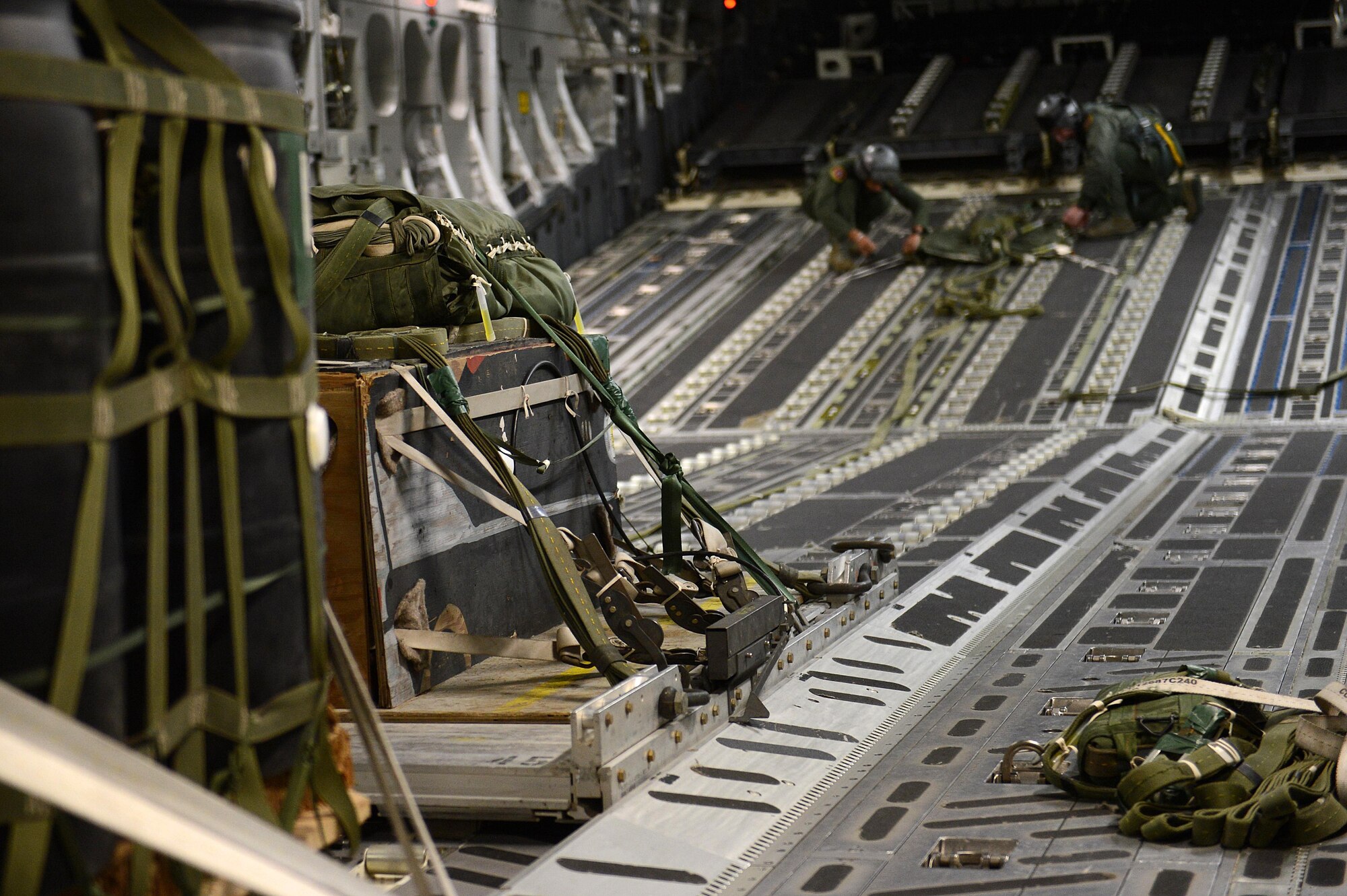 Staff Sgts. Joseph Timpson and Robert Michaels, loadmasters from the 10th Airlift Squadron, tie down a parachute during exercise Rainier War Dec. 10, 2015, before approaching the Rainier drop zone in Washington. The aircrew released three bundles over the DZ during the large formation exercise. (U.S. Air Force photo/Senior Airman Divine Cox)