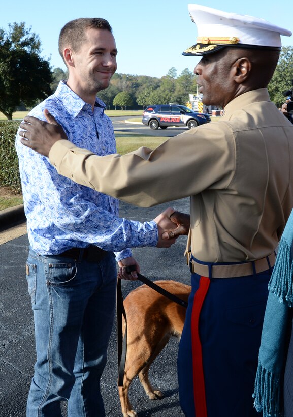 Former Marine Corps handler, David Pond (left), smiles and shakes hands with Col. James C. Carroll III (right), commanding officer, Marine Corps Logistics Base Albany, after officially adopting Pablo, a former military working dog with the base’s, Marine Corps Police Department, during a ceremony held here, Dec. 15.