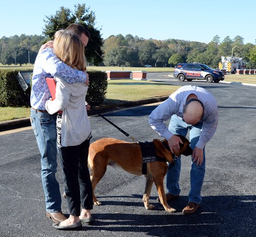 Former Marine Corps handler, David Pond (left), hugs his family after officially adopting Pablo, a former military working dog, Marine Corps Logistics Base Albany’s Marine Corps Police Department, during a ceremony held here, Dec. 15.