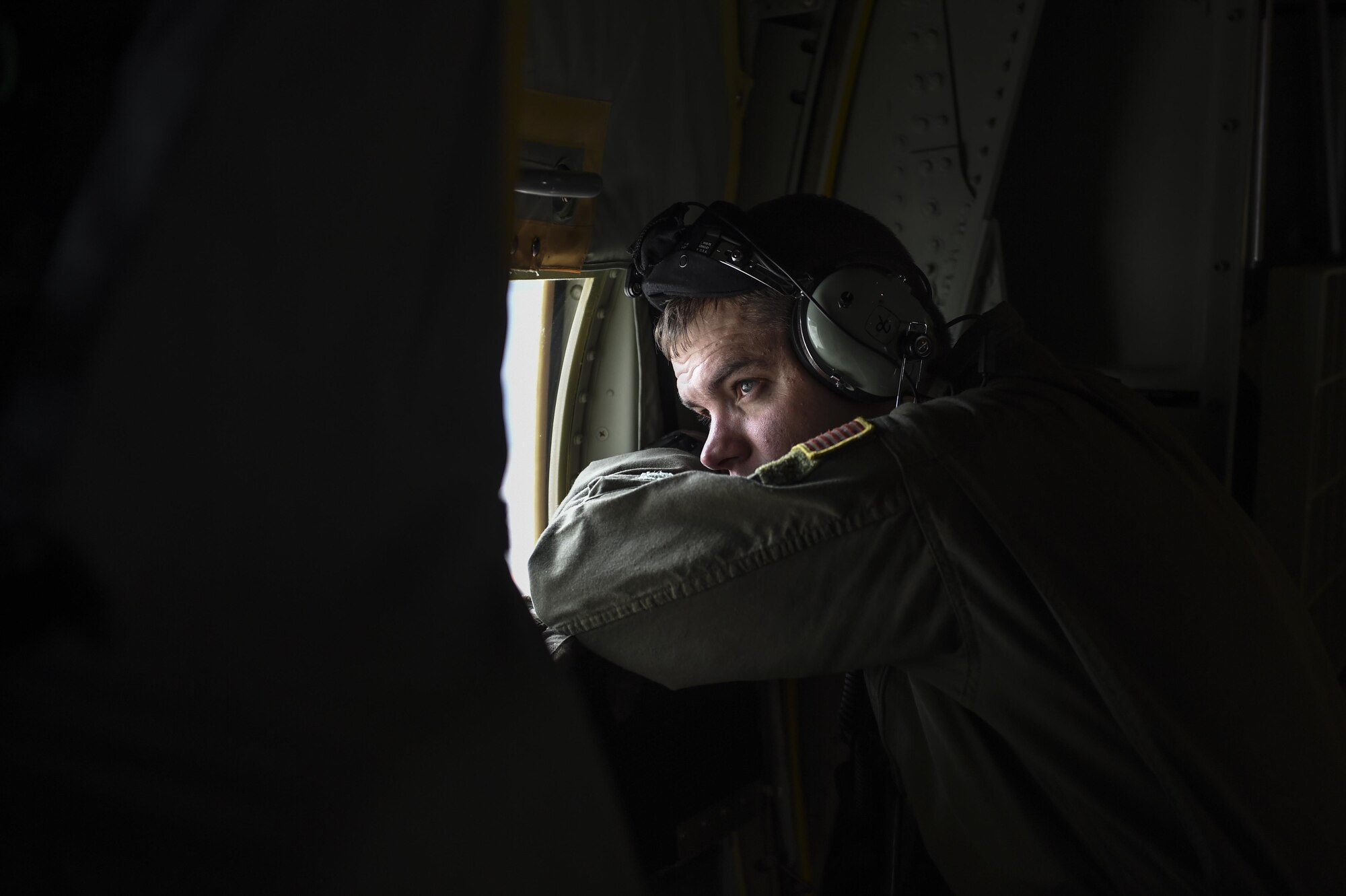 Staff Sgt. Johnny Hooker Jr., a special missions aviator with the 1st Special Operations Group Detachment 2, looks out of the door window of an MC-130J Commando II during a flight to Hurlburt Field, Fla., Dec. 11, 2015. The MC-130J will undergo modifications to become an AC-130J Ghostrider, which will provide the 1 SOW with close air support and air interdiction capabilities. (U.S. Air Force photo by Senior Airman Ryan Conroy)