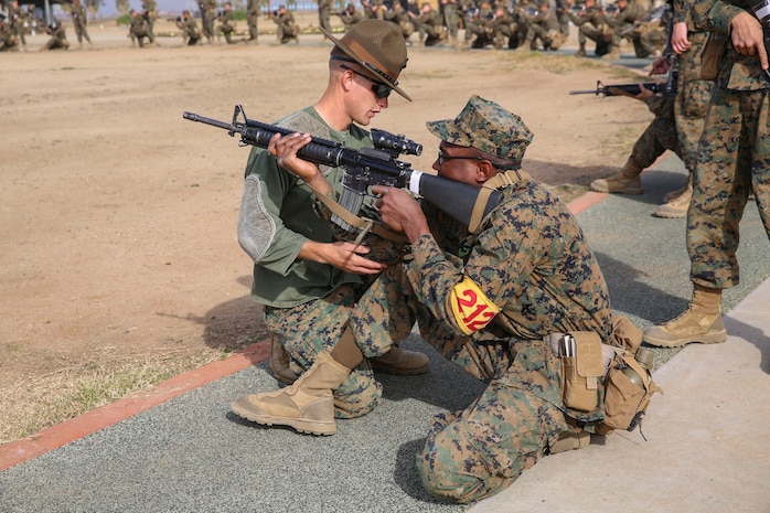Sergeant David A. Phelps, primary marksmanship instructor, Weapons and Field Training Battalion, helps a recruit with his kneeling shooting position during Grass Week at Edson Range, WFTBN, Marine Corps Base Camp Pendleton, Calif., Dec. 9. The PMIs corrected the recruits’ firing positions to ensure the recruits were comfortable and prepared to conduct live firing the following week. Today, all males recruited from west of the Mississippi are trained at MCRD San Diego. The depot is responsible for training more than 16,000 recruits annually. Fox Company is scheduled to graduate Jan. 29.