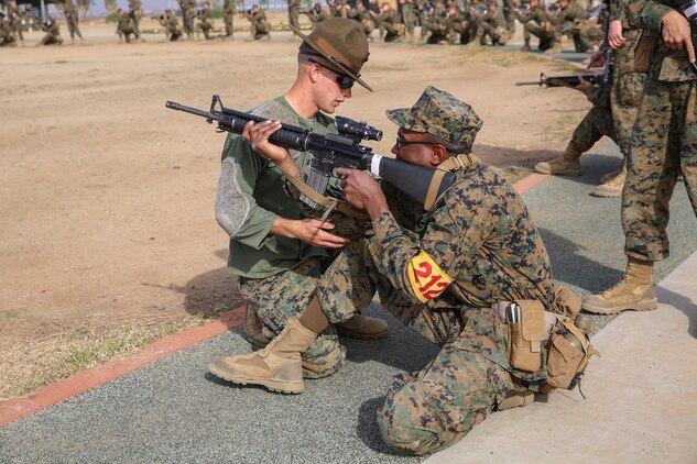 Sergeant David A. Phelps, primary marksmanship instructor, Weapons and Field Training Battalion, helps a recruit with his kneeling shooting position during Grass Week at Edson Range, WFTBN, Marine Corps Base Camp Pendleton, Calif., Dec. 9. The PMIs corrected the recruits’ firing positions to ensure the recruits were comfortable and prepared to conduct live firing the following week. Today, all males recruited from west of the Mississippi are trained at MCRD San Diego. The depot is responsible for training more than 16,000 recruits annually. Fox Company is scheduled to graduate Jan. 29.