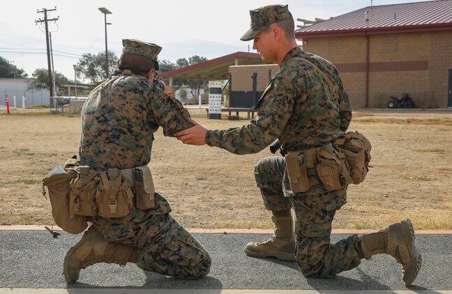 A recruit with Fox Company, 2nd Recruit Training Battalion, assists a fellow recruit with his kneeling shooting position during Grass Week at Edson Range, Weapons and Field Training Battalion, Marine Corps Base Camp Pendleton, Calif., Dec. 9. The recruits spent one week learning about the different fundamentals of firing. Today, all males recruited from west of the Mississippi are trained at MCRD San Diego. The depot is responsible for training more than 16,000 recruits annually. Fox Company is scheduled to graduate Jan. 29.