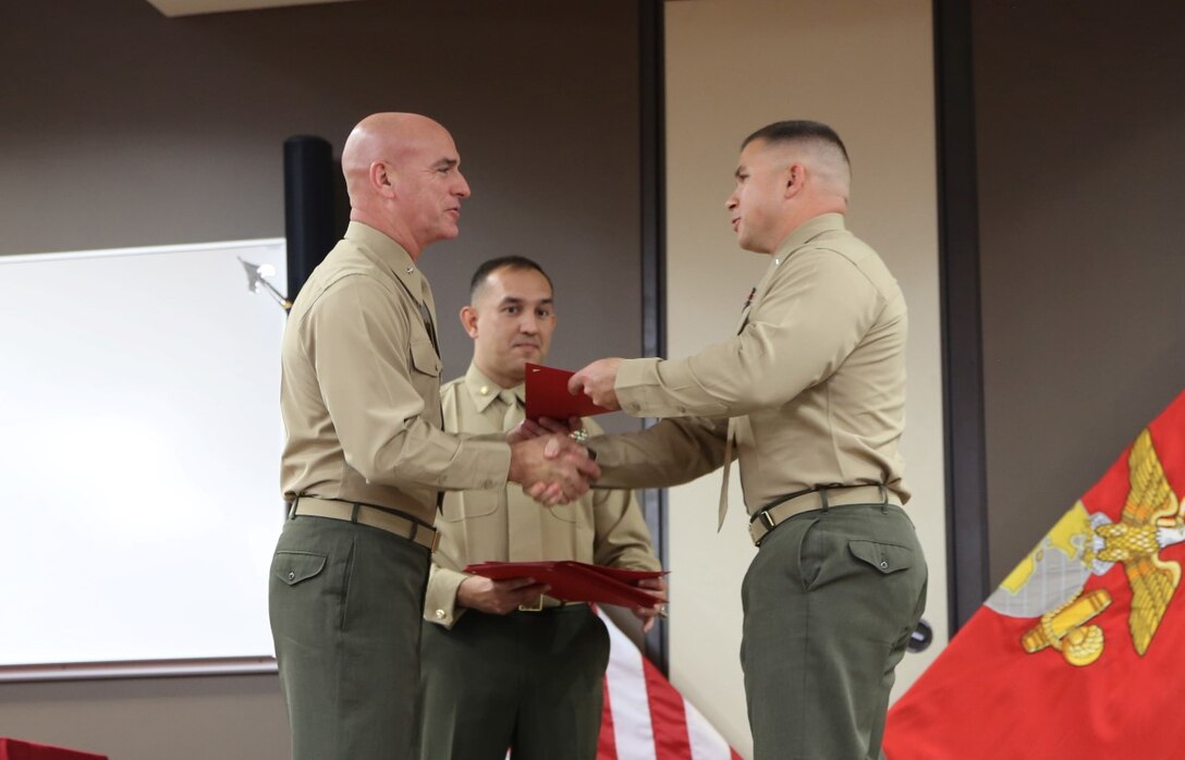 Capt. Chad O. Carlson shakes hands with Brig. Gen. David A. Ottignon as he receives his diploma for graduating the Expeditionary Warfare School, Dec. 11, 2015, at Marine Corps Base Camp Pendleton, Calif. During the course, they discussed the current state of the Marine Corps as well as its future. Carlson and his fellow classmates learned about how plans in process now will positively affect the Marine Corps’ ability to complete its missions in the future. Carlson is a maintenance management officer with Headquarters and Service Company, 3rd Light Armored Reconnaissance Battalion. Ottignon is the commanding general of 1st Marine Logistics Group.
