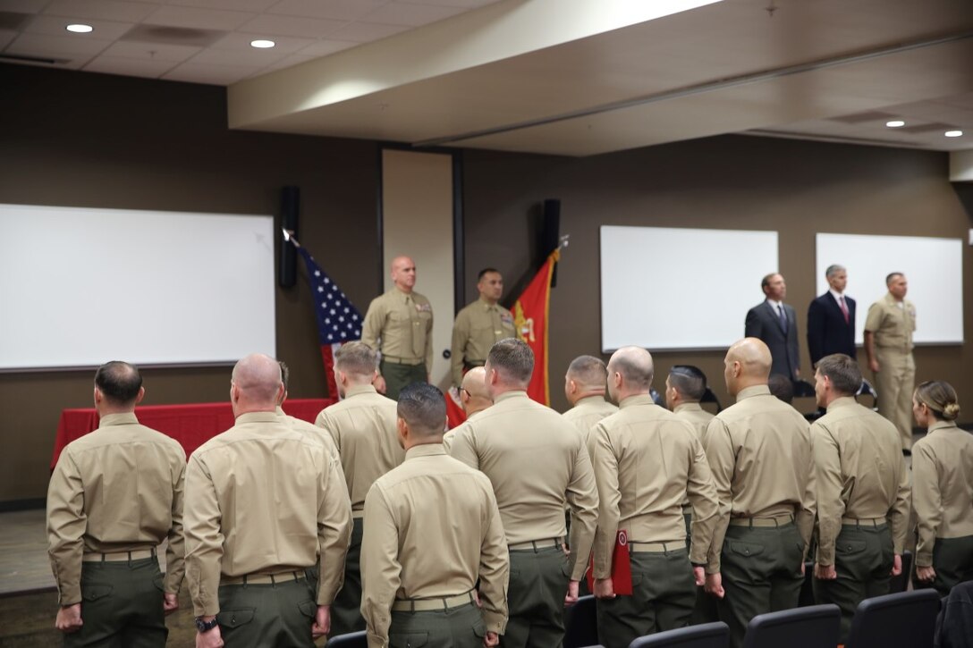 Marines and guests of the Expeditionary Warfare School graduation stand for the "Marines’ Hymn," Dec. 11, 2015, at Marine Corps Base Camp Pendleton, Calif. Singing the hymn is one of many well-kept traditions of the Marine Corps. At the conclusion of the ceremony, Marines are released back to their parent commands as more mission capable and well-rounded officers.