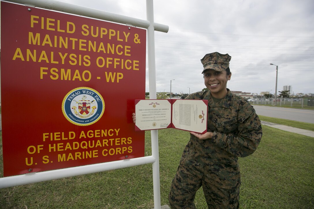 Gunnery Sergeant Anabell Nevels poses with her Meritorious Service Medal citation Dec. 2 aboard Camp Foster, Okinawa, Japan. Along with being award the Meritorious Service Medal, Nevels also received the Military Surface Deployment and Distribution Command 2013 Excellence in Traffic Management award and the 2013 Marine Corps Enlisted Logistician of the Year award. Lacanilao and Nevels are both distribution management analysts with Logistics Modernization Team, Field Supply and Maintenance Analysis Office Western Pacific, Headquarters Marine Corps.