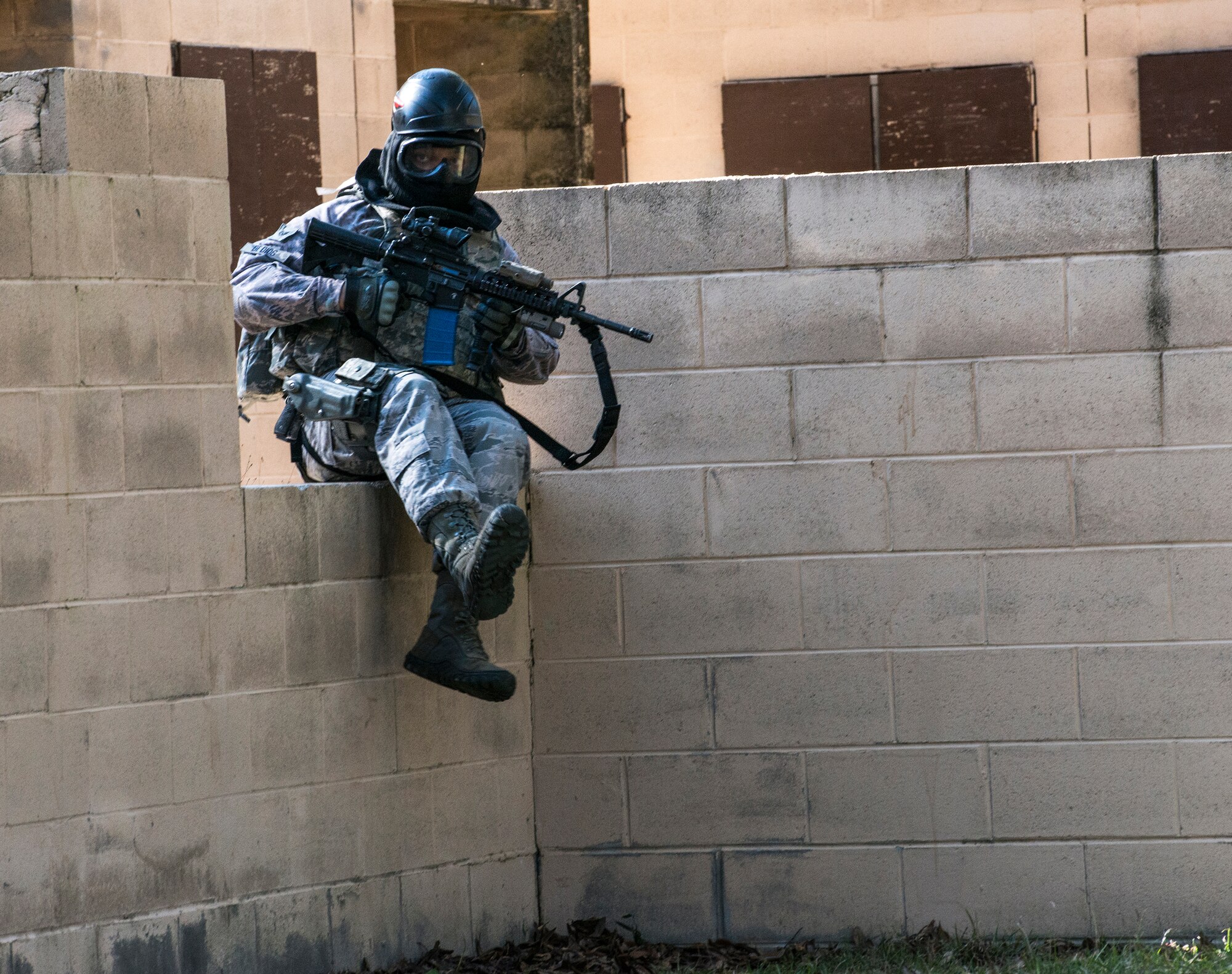 U.S. Air Force Staff Sgt. Adrian De Dios, 822d Base Defense Squadron fire team leader, maneuvers over a wall to engage opposing forces during force-on-force training, Dec. 10, 2015, at Moody Air Force Base, Ga. The quarterly training is used to keep Airmen qualified on their weapons and prepared for battle. (U.S. Air Force photo by Airman 1st Class Lauren M. Johnson/Released)