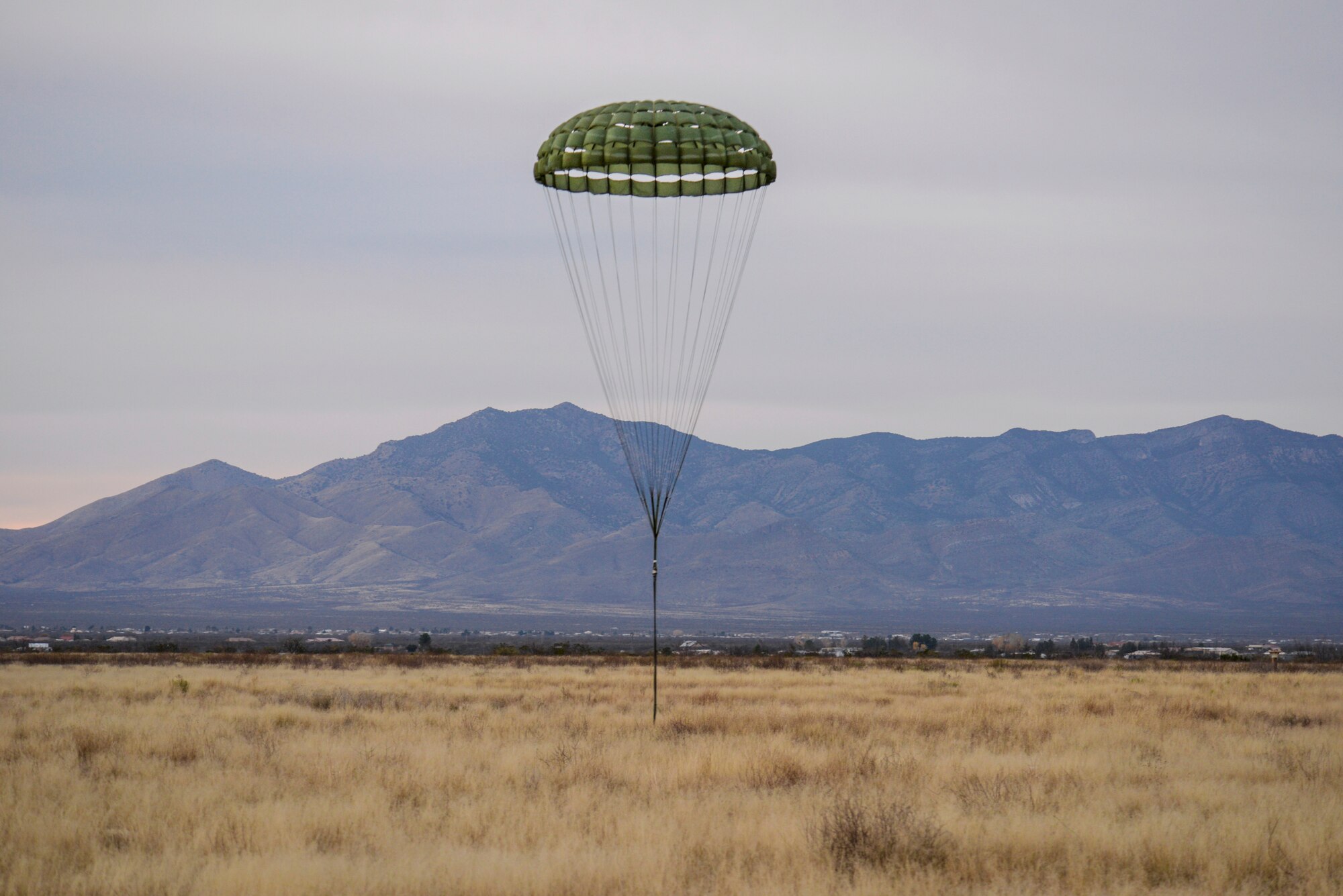 A detached cargo extraction parachute lands in a field after extracting a Humvee from a U.S. Air Force HC-130J Combat King II, from the 79th Rescue Squadron, during the 563d Operations Support Squadron’s aerial delivery and extraction training at Fort Huachuca, Ariz., Dec. 9, 2015.  This training was the first time any rescue operations support squadron packaged and rigged a heavy vehicle without external assistance and the first time a heavy vehicle was dropped by the 79th RQS. (U.S. Air Force photo by Senior Airman Chris Massey/Released)