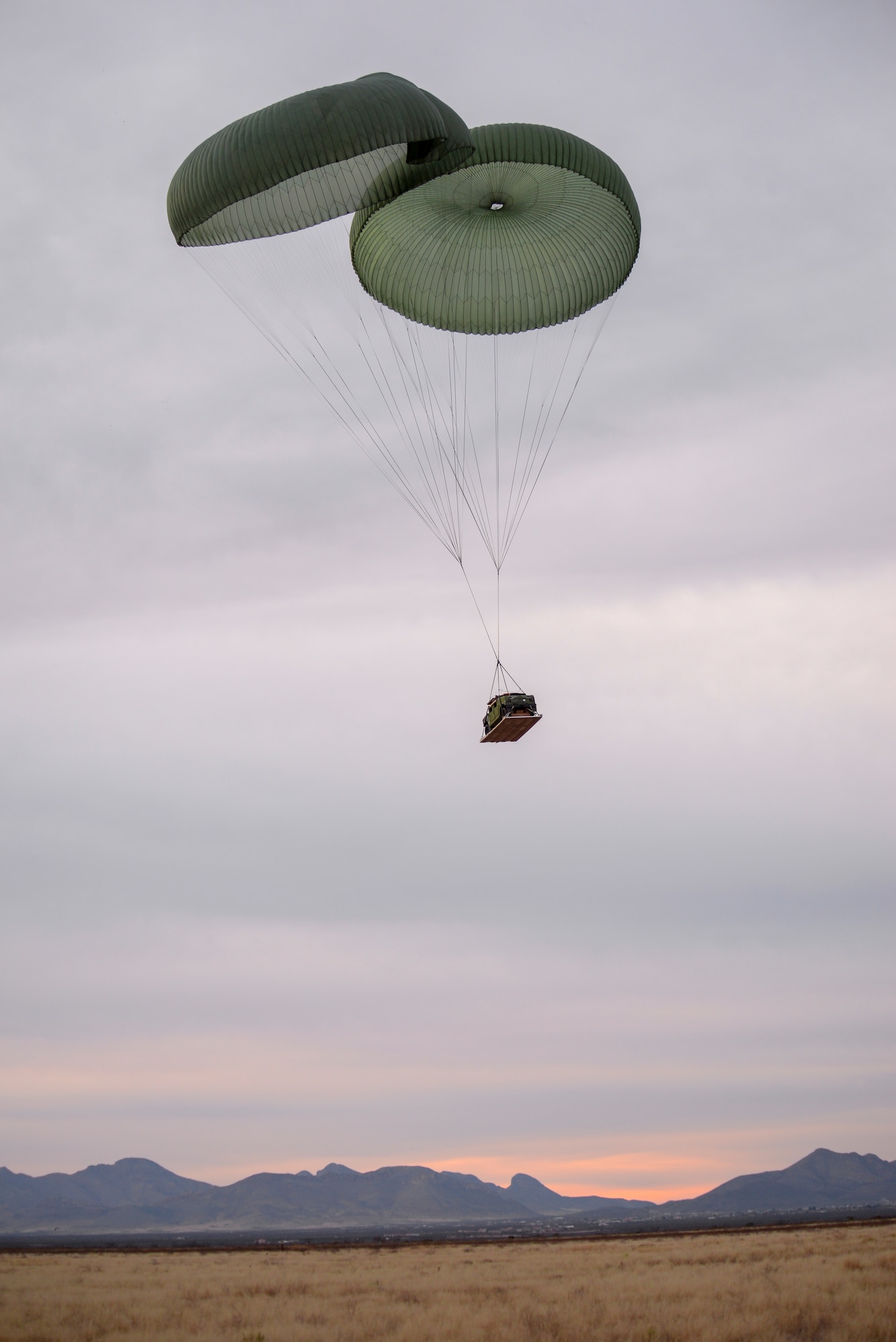 A Humvee drops by parachute during the 563rd Operations Support Squadron’s aerial delivery and recovery training at Fort Huachuca, Ariz., Dec. 9, 2015.  The Humvee was dropped from a 79th Rescue Squadron HC-130J Combat King II stationed at Davis-Monthan Air Force Base. (U.S. Air Force photo by Senior Airman Chris Massey/Released) 