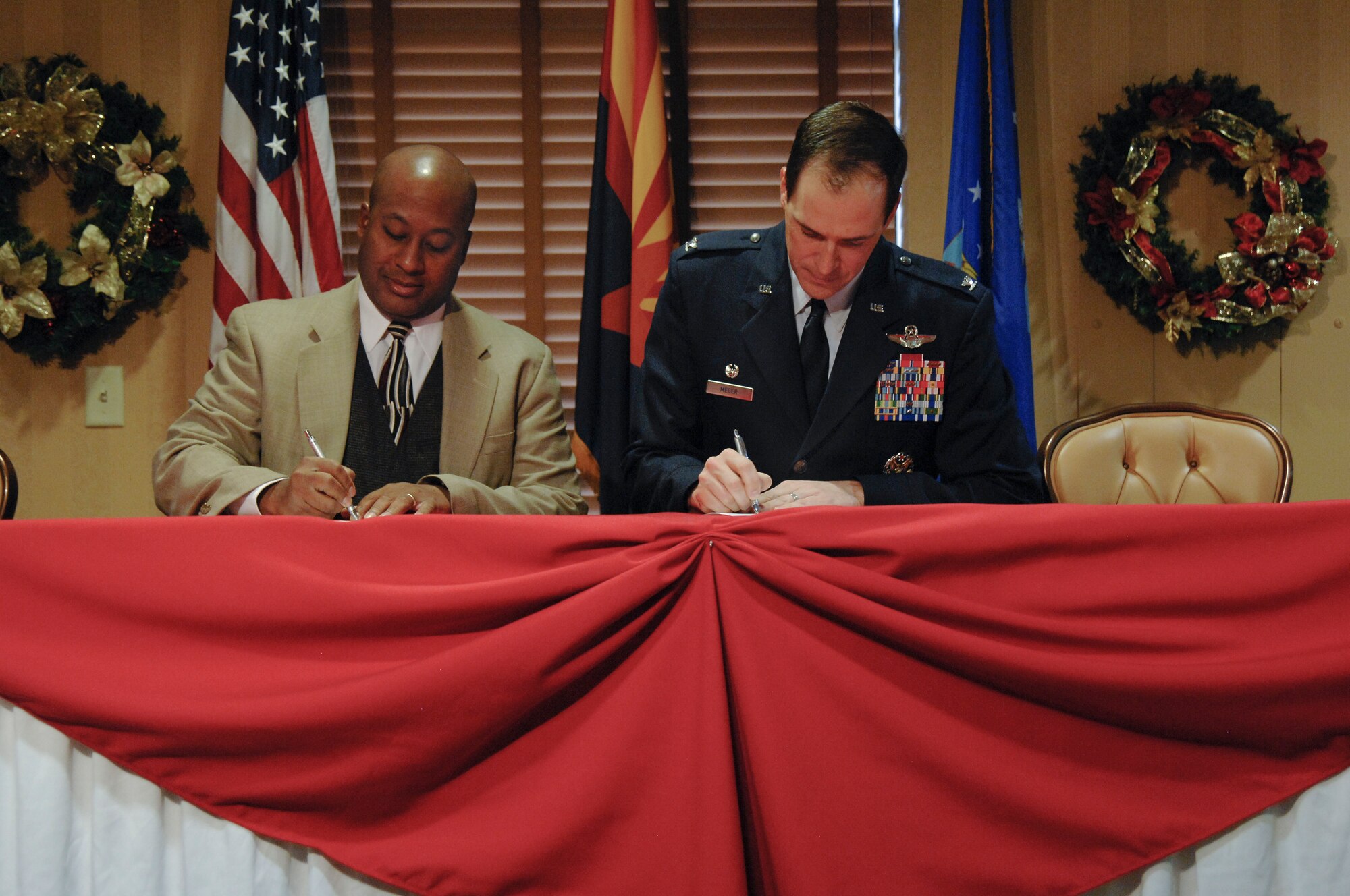 John Voorhees, Pima County Wireless Integrated Network executive director, and U.S. Air Force Col. James Meger, 355th Fighter Wing commander, sign the Emergency Response Communication Interoperability authorization memorandum at Davis-Monthan Air Force Base, Ariz., Dec. 14, 2015. The Emergency Response Communication Interoperability Partnership will increase communication between first responders from D-M and local community in the event of a significant emergency requiring joint response. (U.S. Air Force photo by Staff Sgt. Angela Ruiz/Released)