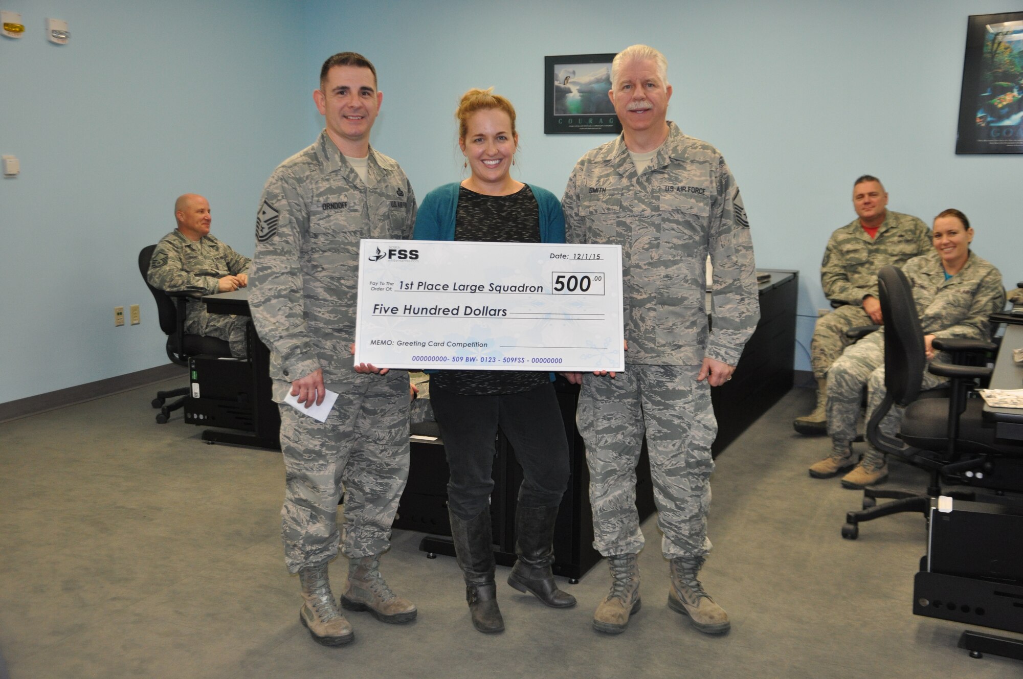 Tech Sergeant Emily Alley, 4422d Fighter Wing Public Affairs NCOIC presents a $500 prize check to Master Sergeant Eric Orndoff, 442 AMXS First Sergeant and Master Sergeant Robin Smith, 442 Airman and Family Readiness Office, Friday.  (U.S. Air Force photo by Captain Jeff Kelly/Released)