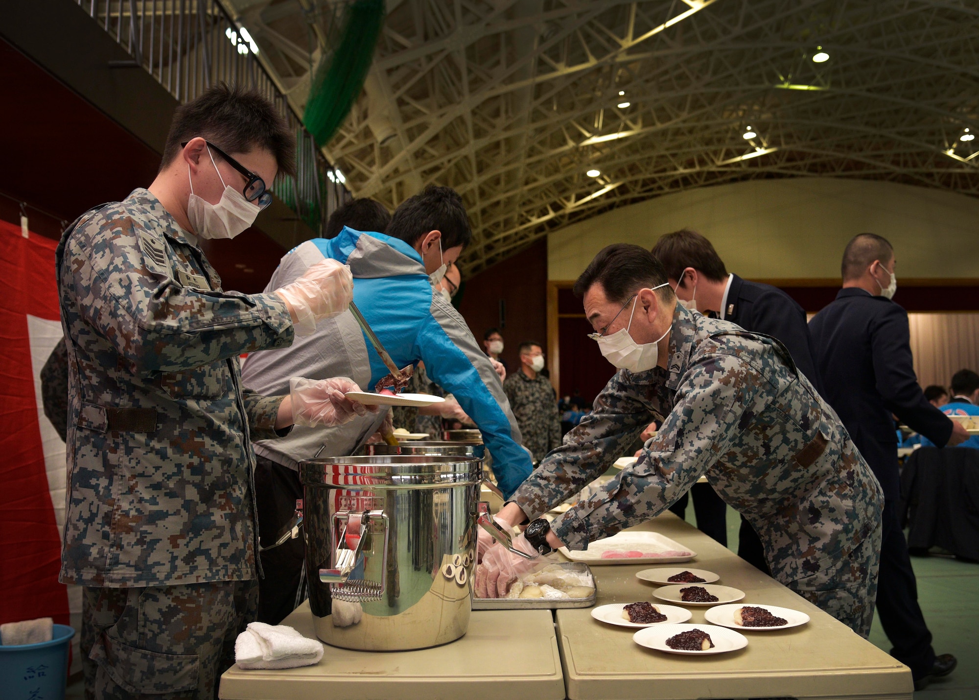 Japan Air Self-Defense Force volunteers serve mochi in various ways during the annual Mochi Pounding Ceremony at Misawa Air Base, Japan, Dec. 15, 2015. After participants pounded the mochi in large wooden mortars, they sampled different ways to traditionally eat mochi as part of the New Year celebrations. (U.S. Air Force photo by Senior Airman Deana Heitzman/Released)  