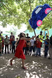 A Honduran girl strikes a piñata during Chapel Hike 65, Honduras, Dec. 12, 2015. Chapel hikes like this one help build bonds with local communities. (U.S. Air Force photo by Senior Airman Westin Warburton/Released)