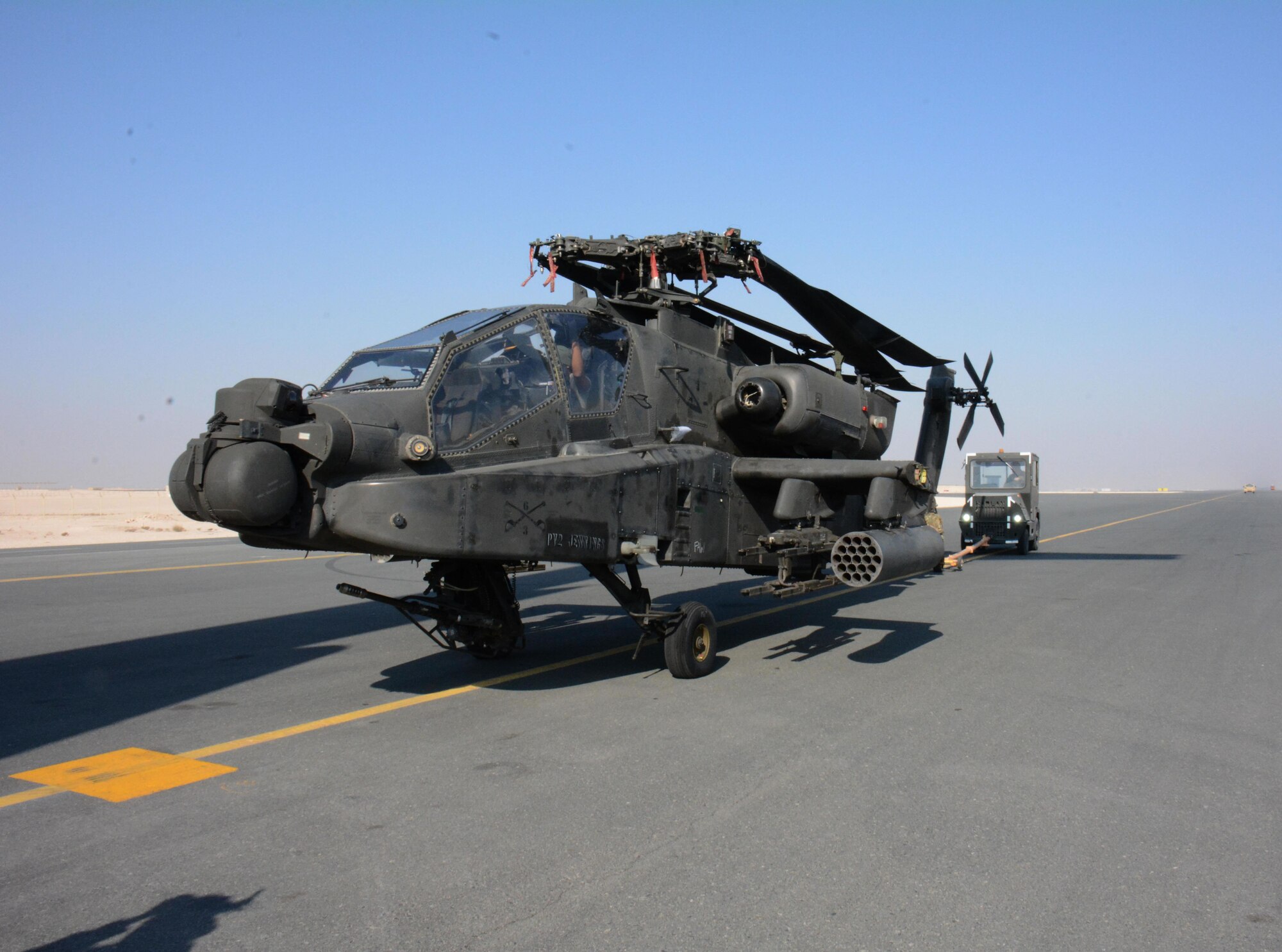 One of two apache helicopters from Fort Bliss, Texas is transported to its parking location Dec. 13 at Al Udeid Air Base, Qatar. The helicopters were delivered by a C-17 Globemaster III deployed from the 62nd Airlift Wing at Joint Base Lewis-McChord, Washington. The helicopters are scheduled to take part in the annual Qatar National Day Parade set for Dec. 18. (U.S. Air Force photo by Tech. Sgt. James Hodgman/Released)