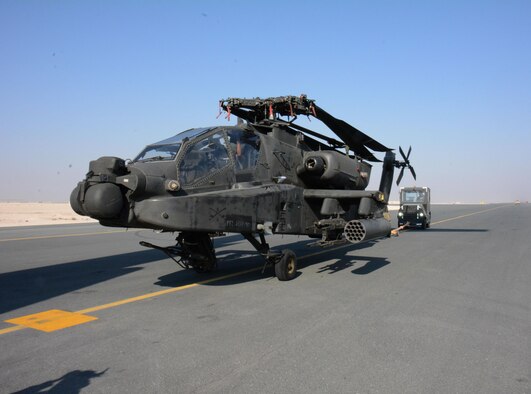One of two apache helicopters from Fort Bliss, Texas is transported to its parking location Dec. 13 at Al Udeid Air Base, Qatar. The helicopters were delivered by a C-17 Globemaster III deployed from the 62nd Airlift Wing at Joint Base Lewis-McChord, Washington. The helicopters are scheduled to take part in the annual Qatar National Day Parade set for Dec. 18. (U.S. Air Force photo by Tech. Sgt. James Hodgman/Released)