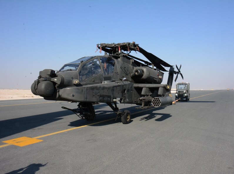 One of two apache helicopters from Fort Bliss, Texas is transported to its parking location Dec. 13 at Al Udeid Air Base, Qatar. The helicopters were delivered by a C-17 Globemaster III deployed from the 62nd Airlift Wing at Joint Base Lewis-McChord, Washington. The helicopters are scheduled to take part in the annual Qatar National Day Parade set for Dec. 18. (U.S. Air Force photo by Tech. Sgt. James Hodgman/Released)