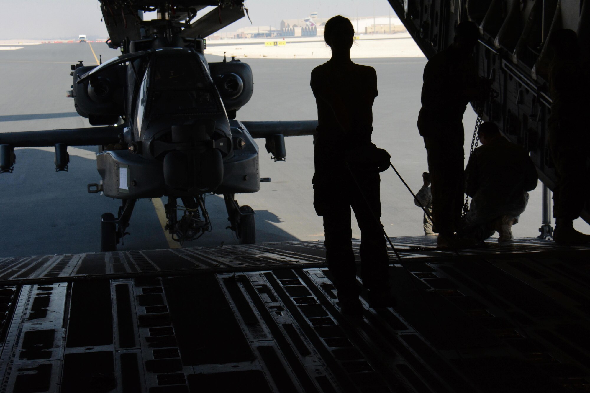 Soldiers deployed from the 3-6 Cavalry Regiment at Fort Bliss, Texas work to move one of two Apache helicopters out of a C-17 Globemaster III at Al Udeid Air Base, Qatar Dec. 13. The C-17, which is deployed from the 62nd Airlift Wing at Joint Base Lewis-McChord, Washington, delivered the helicopters. The helicopters are scheduled to take part in the annual Qatar National Day Parade set for Dec. 18. (U.S. Air Force photo by Tech. Sgt. James Hodgman/Released)