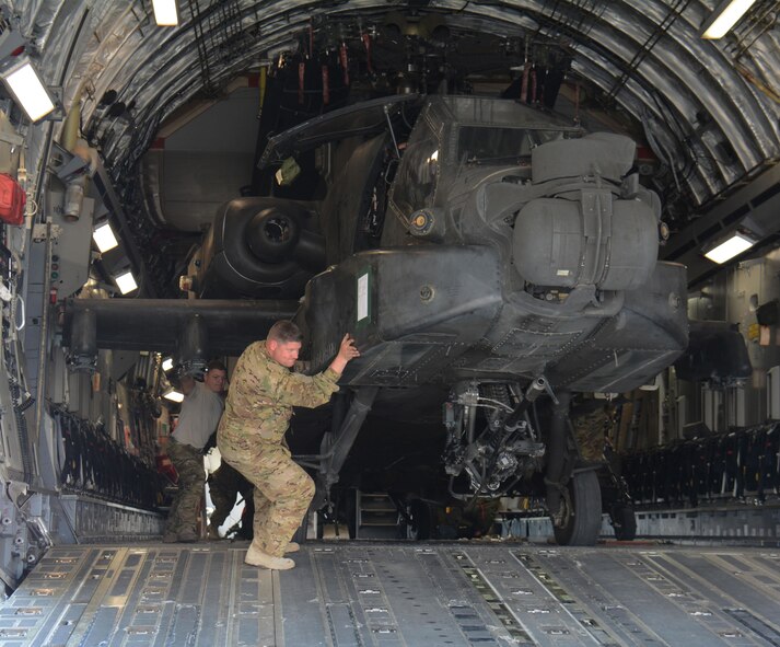 3-6 Heavy Cavalry Regiment soldiers deployed from Fort Bliss, Texas work to move one of two Apache helicopters out of a C-17 Globemaster III at Al Udeid Air Base, Qatar Dec. 13. The C-17, which is deployed from the 62nd Airlift Wing at Joint Base Lewis-McChord, Washington, delivered the helicopters. The helicopters are scheduled to take part in the annual Qatar National Day Parade set for Dec. 18. (U.S. Air Force photo by Tech. Sgt. James Hodgman/Released)