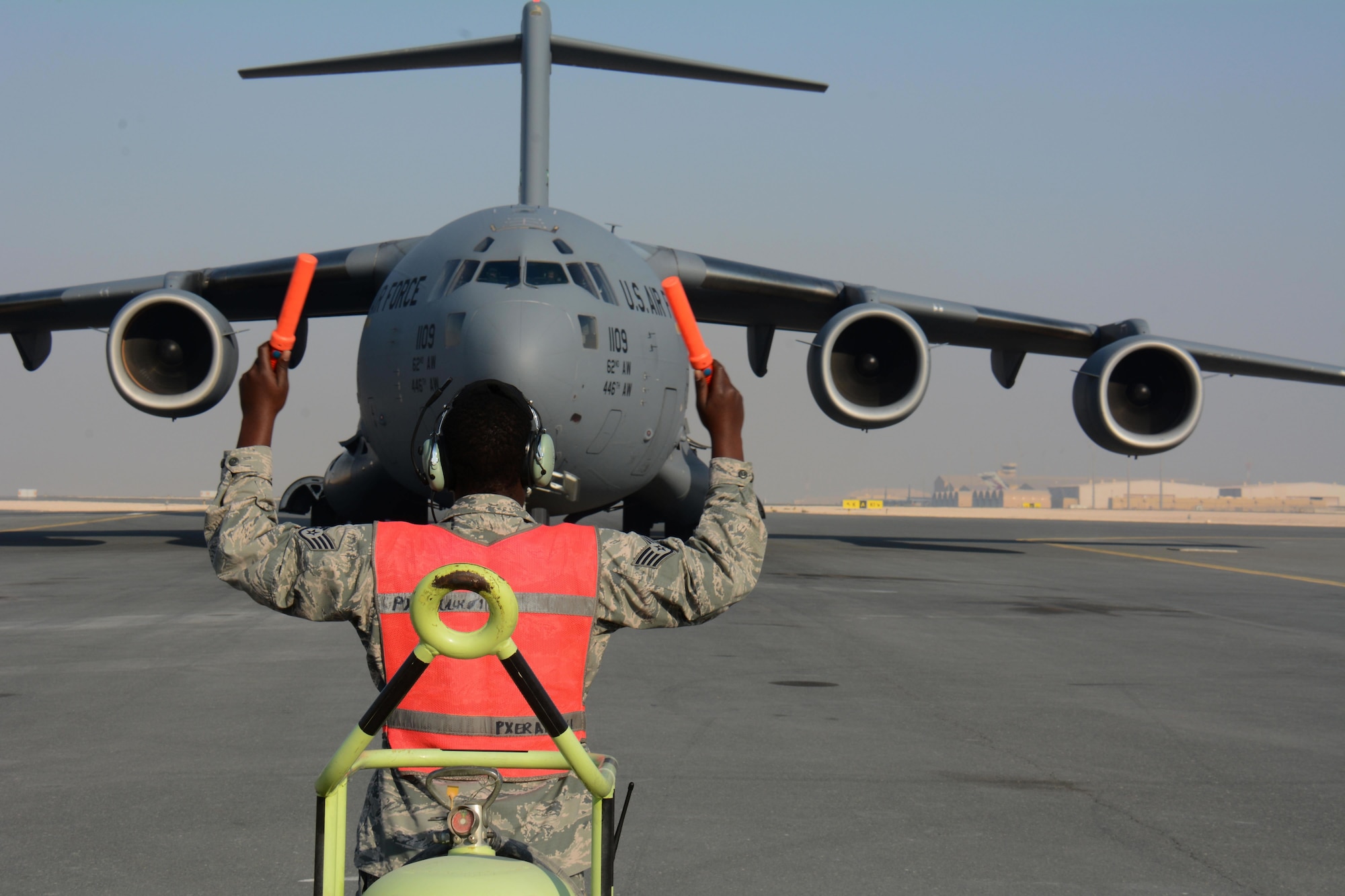 Staff Sgt. Berry Lynch, 8th Expeditionary Air Mobility Squadron avionics specialist, directs a C-17 Globemaster III to its parking location at Al Udeid Air Base, Qatar Dec. 13. The aircraft delivered two Apache helicopters from Fort Bliss, Texas. The helicopters are scheduled to take part in the annual Qatar National Day Parade set for Dec. 18. (U.S. Air Force photo by Tech. Sgt. James Hodgman)