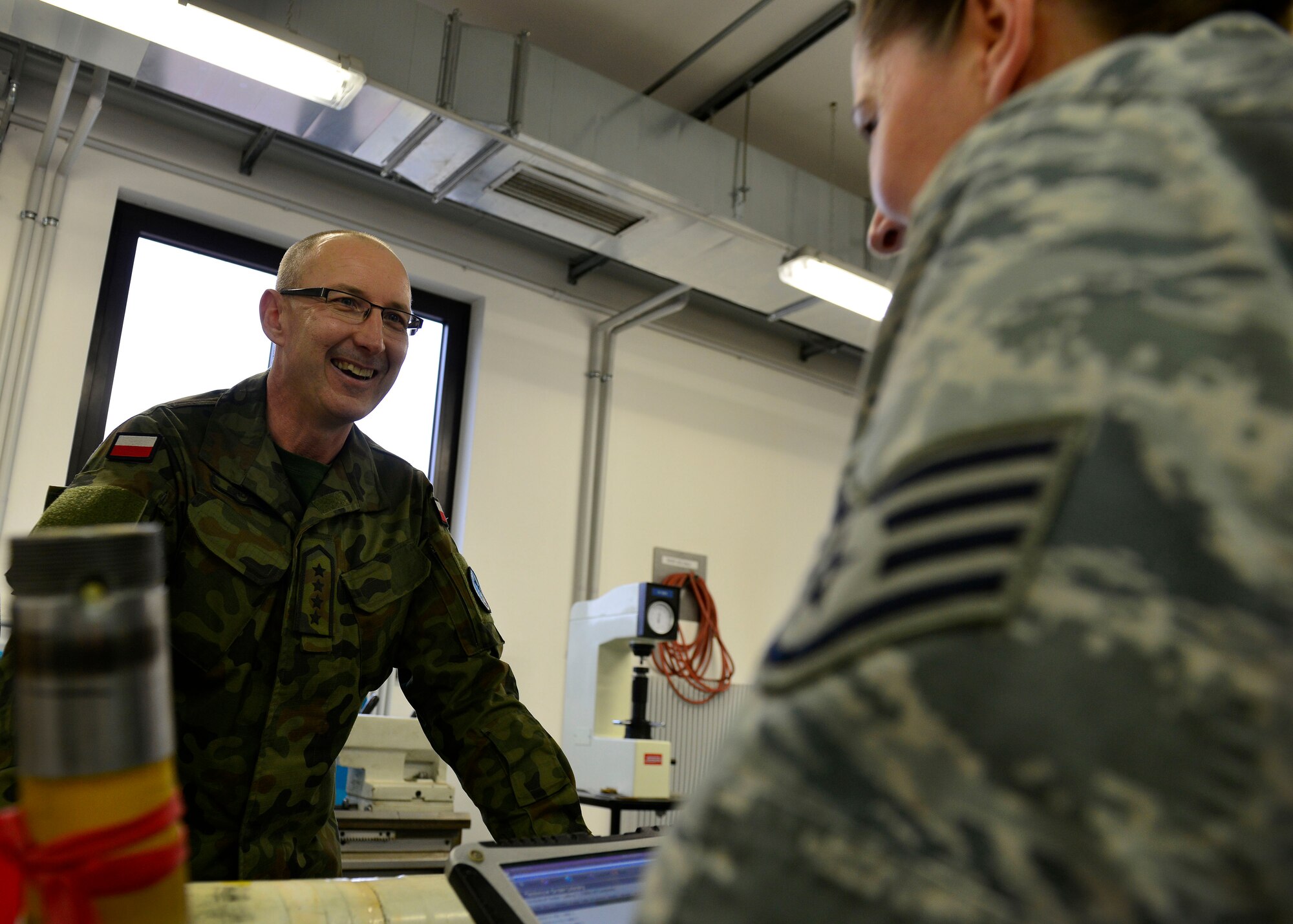 Polish Chief Warrant Officer 5 Sebastian Krogzek, a Polish air force metals technology technician, inspects landing gear parts with U.S. Air Force Staff Sgt. Lisa McDermott, 31st Maintenance Squadron aircraft metals technology craftsman, during a joint training event, Dec. 15, 2015, at Aviano Air Base, Italy. The training afforded U.S. and Polish air force members the opportunity to better understand how they each maintain F-16 Fighting Falcon parts. (U.S. Air Force photo by Airman 1st Class Cary Smith/Released)