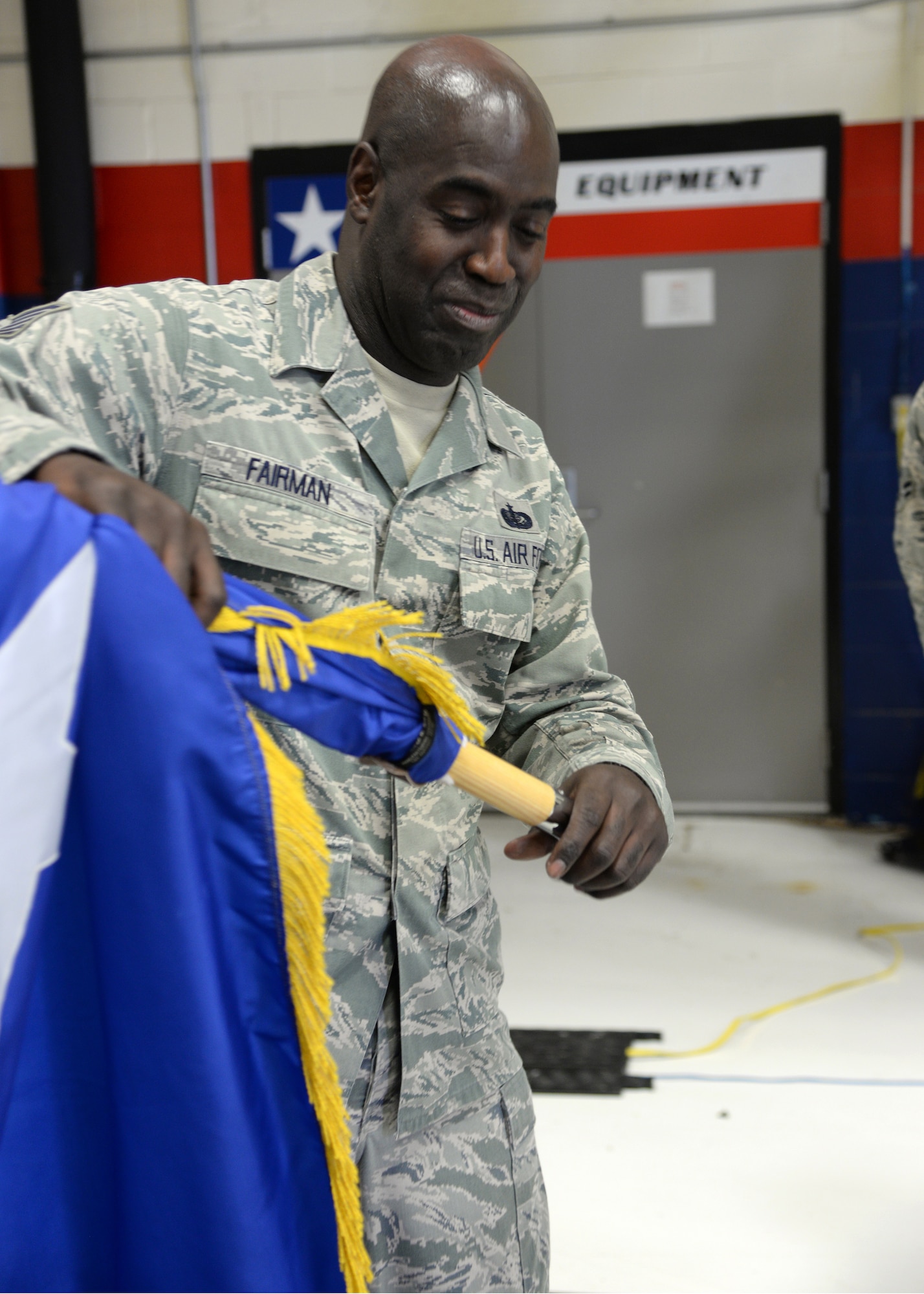 Tech. Sgt. Kevin Fairman, a member of the 149th Fighter Wing, puts away a two-star command flag after an all call held Dec 10 in a maintenance hangar at Joint Base San Antonio-Lackland, Texas. 