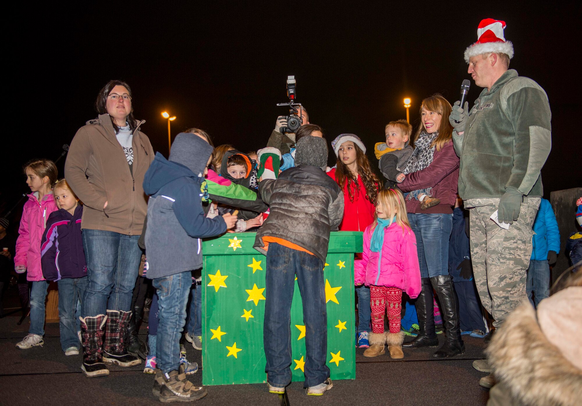 U.S. Air Force Col. Joe McFall, 52nd Fighter Wing commander, and the family members of deployed Spangdahlem Airmen turn on the Holiday Tree lights together during the annual tree-lighting ceremony at the Bowling Alley at Spangdahlem Air Base, Germany, Dec. 10, 2015. McFall invited family members of deployed Spangdahlem Airmen to light the tree together to officially signal the beginning of the holiday season. (U.S. Air Force photo by Airman 1st Class Timothy Kim/Released)