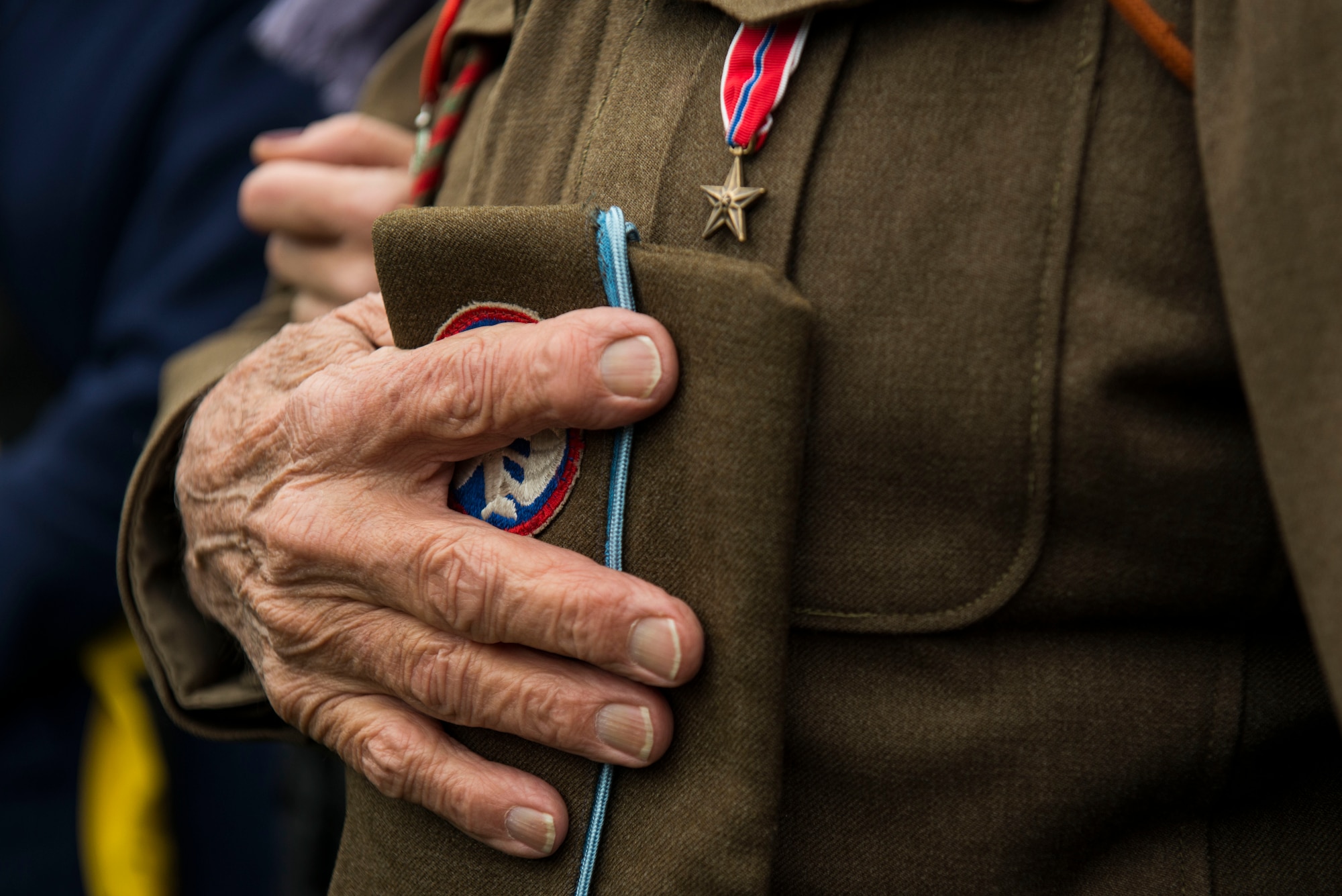 Vincent Speranza, U.S. Army retired, Company H, 501st Parachute Infantry Regiment, 101st Airborne Division, infantryman machine gunner, places his hand over his heart to pay respect during a Battle of the Bulge ceremony in Bertogne, Belgium, Dec. 13, 2015. In 1944, three weeks after arriving in France as a replacement soldier, Speranza was assigned to the defense of Bastogne, Belgium against German attacks. Speranza later participated in the liberation of the concentration camp at Dachau, Germany. (U.S. Air Force photo by Staff Sgt. Christopher Ruano/Released)