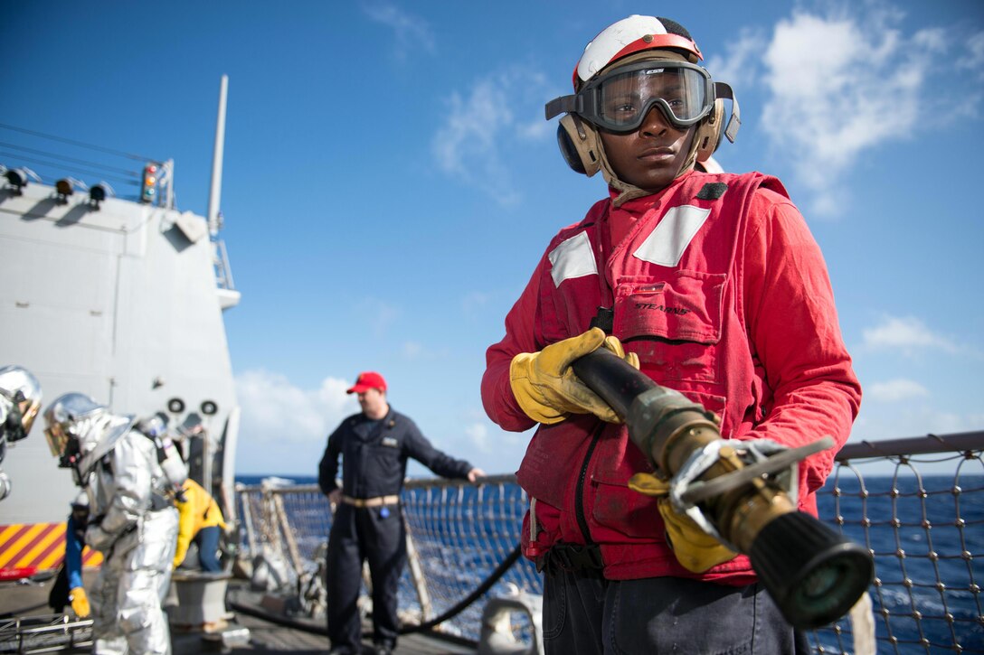 Petty Officer 2nd Class Natasha McNeil mans a hose during a damage control drill on the flight deck of the USS Mustin in the Philippine Sea, Dec. 9, 2015. The Mustin is on patrol in the U.S. 7th Fleet area of responsibility in support of security and stability in the Indo-Asia Pacific region. U.S. Navy photo by Petty Officer 2nd Class Christian Senyk