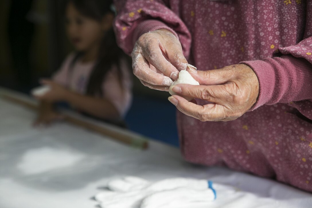 A Japanese staff member at Cultural Day in Tsuzu, Japan, demonstrates how to knead mochi after it is pounded, Dec. 12, 2015. This cultural exchange provides both the American and Japanese communities an opportunity to interact, learn about each other’s culture, and make new friends through games, food, and arts and crafts.