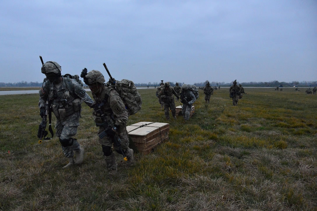 U.S. soldiers pull door bundles of supplies after exiting a U.S. Air Force C-130 Hercules aircraft during Exercise Rock Nemesis at Rivolto Air Base, Italy, Dec. 4, 2015. U.S. Army photo by Paolo Bovo