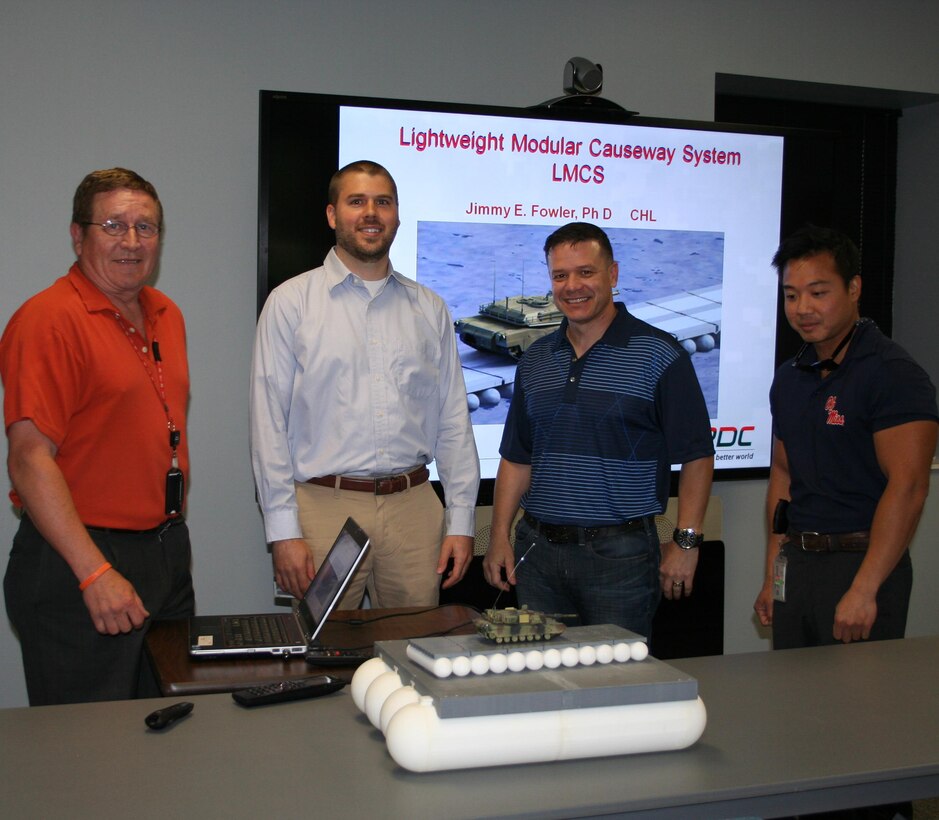 Dr. Jimmy Fowler and Dr. Mark Wahl  explaining the table model and briefing the Lightweight Modular Causeway System (LMCS) to MAJ Wallace Mattos, the Military Personnel Exchange Program Officer.  Also shown is Bo Tennant, Security.  MAJ Mattos was  learning about the program to support his upcoming mission representing ERDC in Brazil.