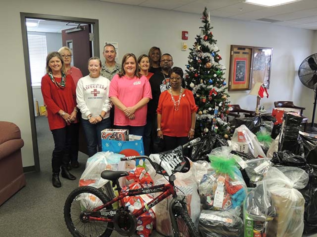 Air Force Col. Rob Bloker, industrial support activity commander for DLA Aviation at Warner Robins, Georgia, poses with DLA Aviation employees next to gifts they collected Dec. 11, 2015 for 30 Salvation Army Christmas angels.    