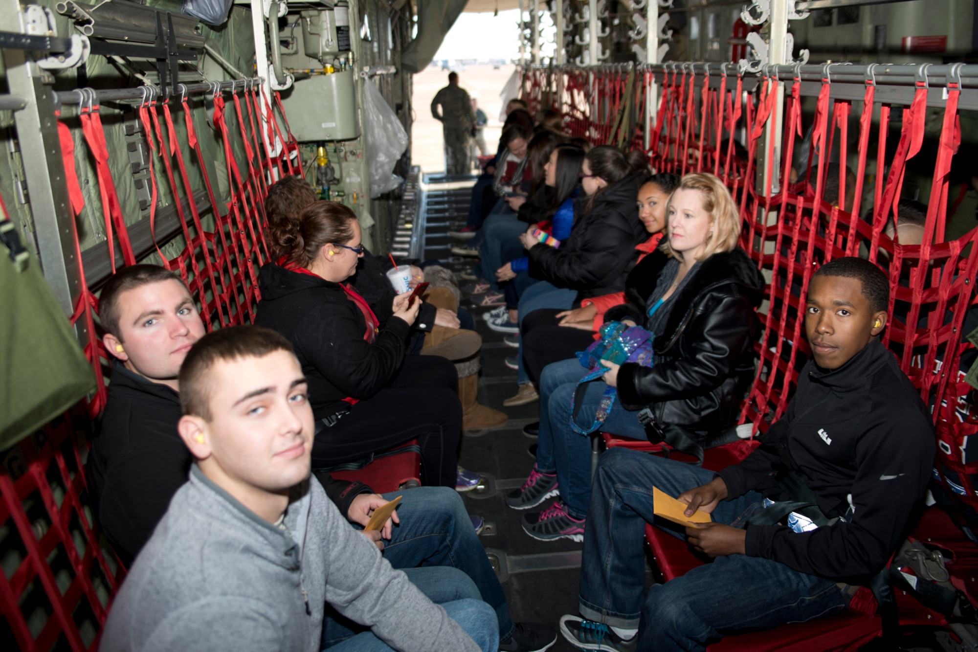 Spouses from the 913th Airlift Group try to get comfortable on seats made of nylon fabric wrapped around a lightweight aluminum alloy frame, while awaiting takeoff onboard a C-130H Hercules aircraft at Little Rock Air Force Base, Ark,., Dec. 5, 2015. The spouses were part of an incentive flight hosted by the 913th Airlift Group so they could better understand what their spouses do on a daily basis. (U.S. Air Force photo by Capt. Casey Staheli/Released)