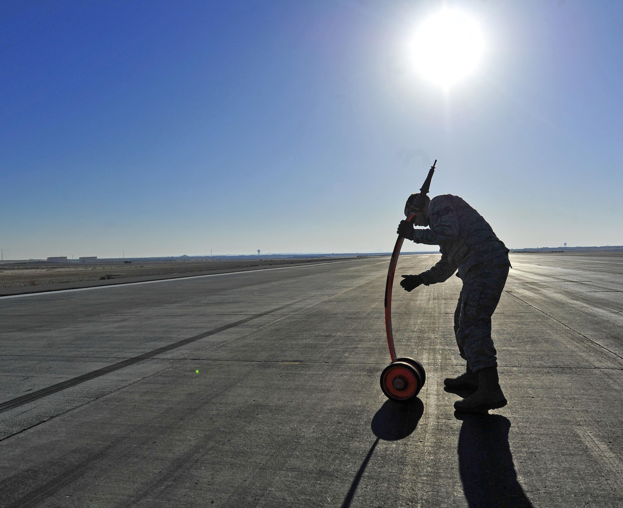 A Dragon Aircraft Maintenance Unit Airman recovers and inspects a pogo stick on the runway at an undisclosed location in Southwest Asia, Dec. 10, 2015. Pogo sticks are approximately four-foot long, spring aluminum devices that help the U-2 Dragon Lady aircraft balance its 105-foot wing span while on the ground. (U.S. Air Force photo by Staff Sgt. Kentavist P. Brackin/released)