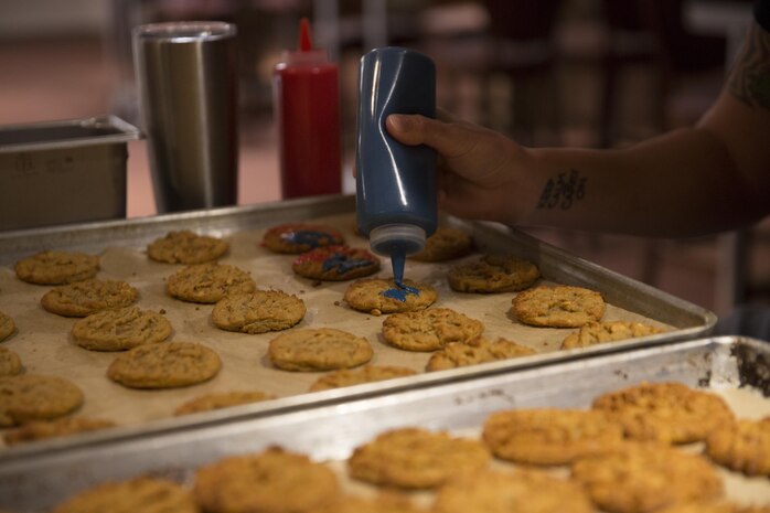 A volunteer decorates patriotic-themed cookies for service members, during Treats for Troops at the Frontline Restaurant, Dec. 8, 2015. More than 2,000 cookies were decorated to be handed out to Combat Center Marines and sailors. (Official Marine Corps photo by Lance Cpl. Connor Hancock/Released)