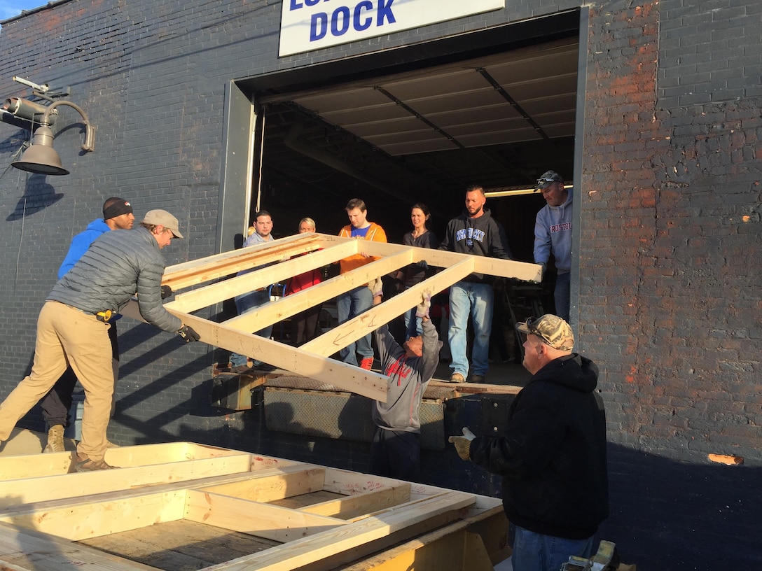The team pitches in to load a wall frame constructed at the Habitat for Humanity workshop for transport to the construction site. 