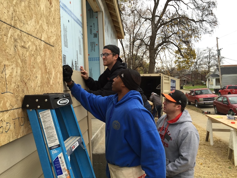 Master Sgt. Kelvin France, Chris Brackett (rear), and Bjorn Hale (right) install siding on a Habitat for Humanity home during a Corps service outing Nov. 21, 2015.