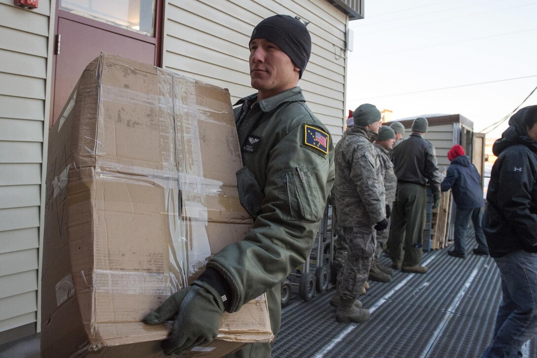 Alaska Air National Guard Senior Airman Casey Hill delivers a box of donated presents to the residents of St. Mary's, Alaska, during Operation Santa Claus, Dec. 5, 2015. U.S. Air Force photo by Alejandro Pena