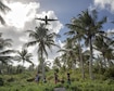 Islanders watch a C-130 Hercules fly overhead during Operation Christmas Drop 2015 at Fais Island, Federated States of Micronesia, Dec. 8, 2015. A C-130 assigned to the 36th Airlift Squadron delivered over 800 pounds of supplies to the island during the operation. This year marked the first ever trilateral Operation Christmas Drop where the Air Force, Japan Air Self-Defense Force and the Royal Australian Air Force worked together to provide critical supplies to 56 Micronesian islands. (U.S. Air Force photo/Osakabe Yasuo)